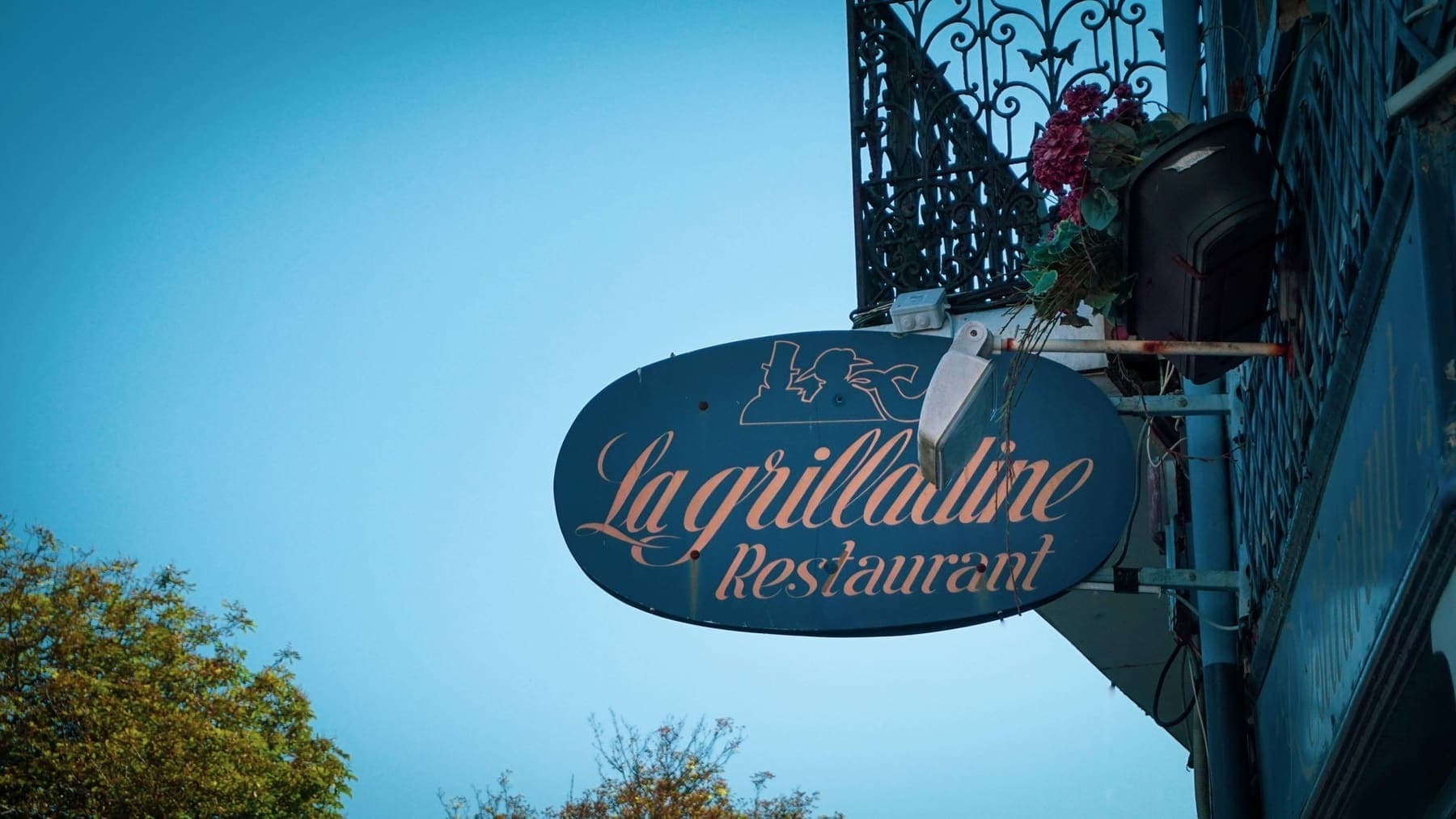 L'enseigne « La Grilladine — Restaurant » au-dessus de la rue